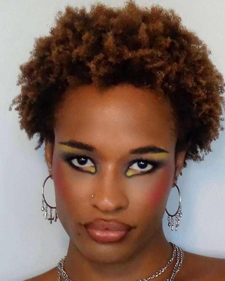 Close up portrait of Jules Crosby with edgy editorial makeup looking at the camera against a white backdrop
